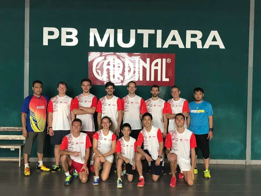 Les stagiaires, en maillots blanc et rouge, avec des joueurs du club devant le mur du PB Mutiara