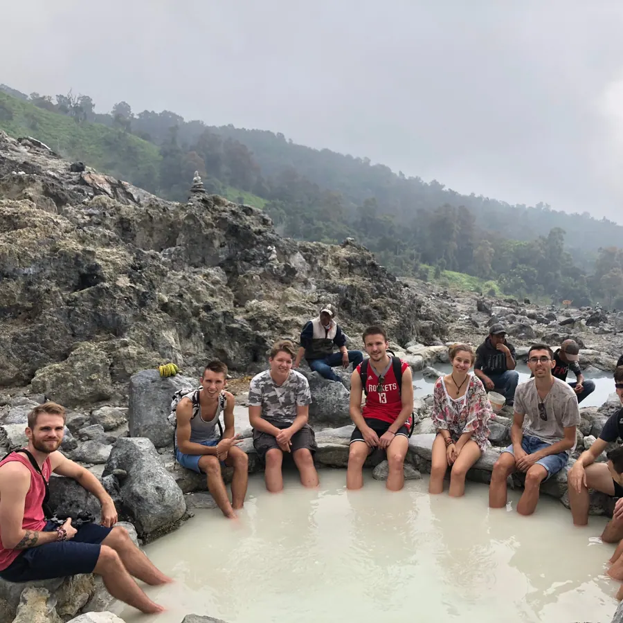 Les stagiaires assis dans une source chaude, au milieu des roches volcaniques